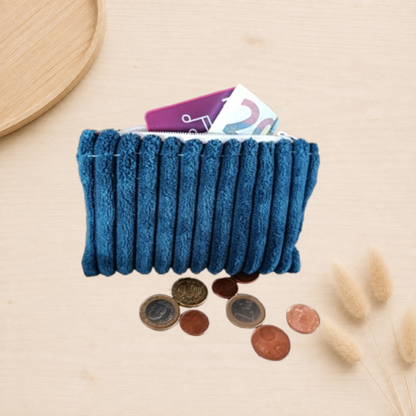 Porte monnaie ouvert en velours côtelé bleu, avec doublure et fermeture éclair blanche. Présentation, mise en scène